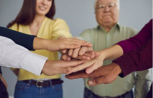 A picture representing togetherness. People are putting their hands together to showcase that they are committed to work together.