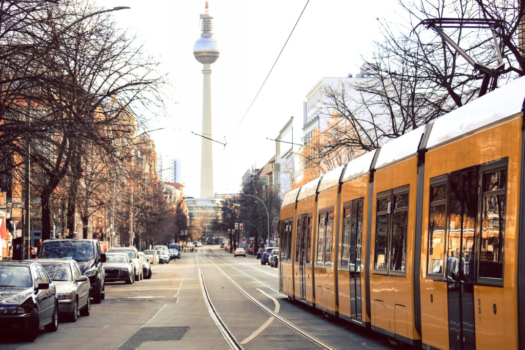 A photo of a street of Berlin with one of the most famous sights and a tram.